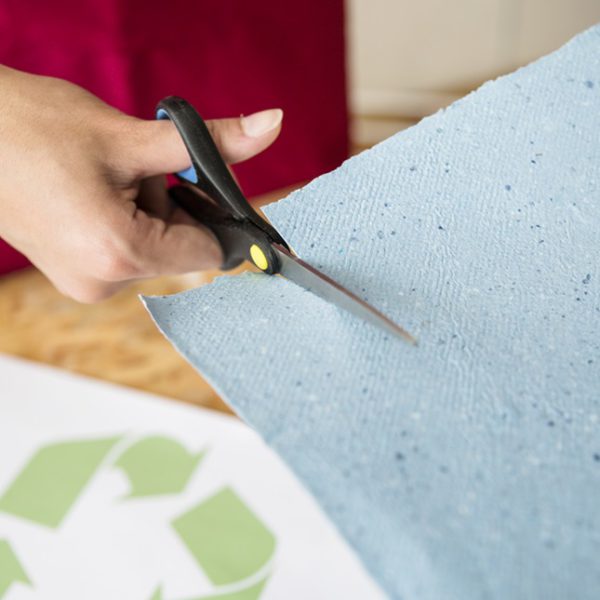 close-up-woman-s-hand-cutting-blue-paper-with-scissors